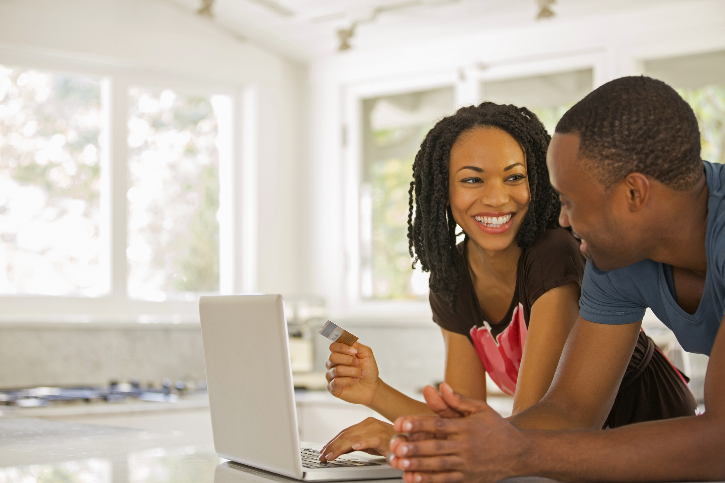 Happy couple shopping online at laptop in kitchen